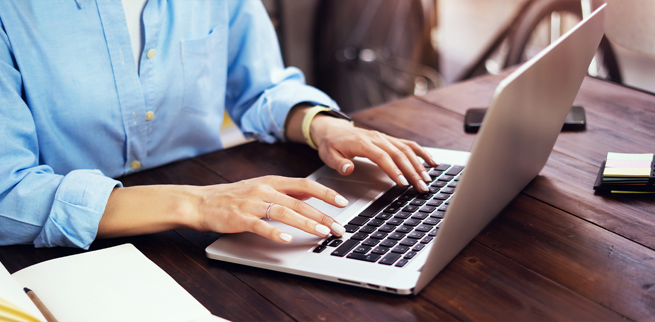 a person using a laptop computer sitting on top of a wooden table