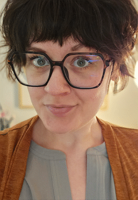 a close up of a person wearing glasses and looking at the camera