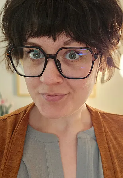 a close up of a person wearing glasses and looking at the camera