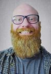a close up of a man wearing glasses and smiling at the camera