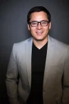 a man wearing a suit and tie smiling at the camera