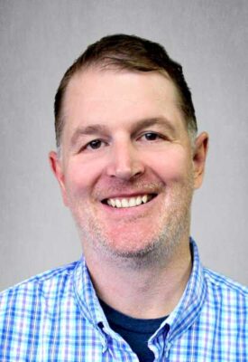 a man wearing glasses and smiling at the camera