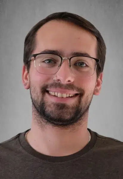 a man wearing glasses and smiling at the camera