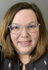 a close up of a person wearing glasses and smiling at the camera