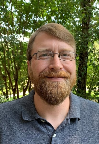 a man wearing glasses and smiling at the camera