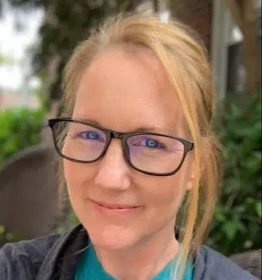 a person wearing glasses and smiling at the camera