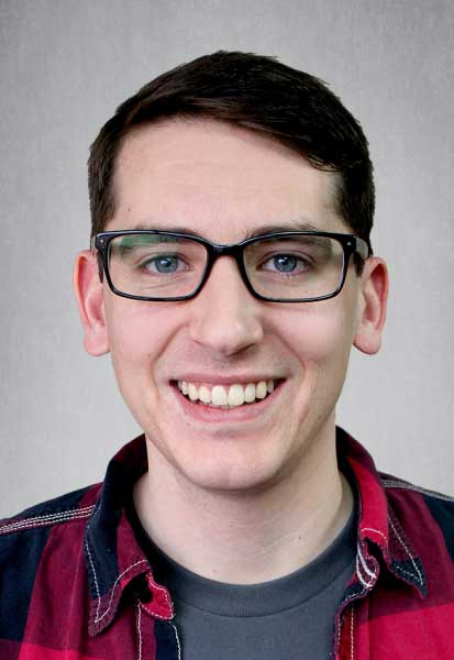 a man wearing glasses and smiling at the camera